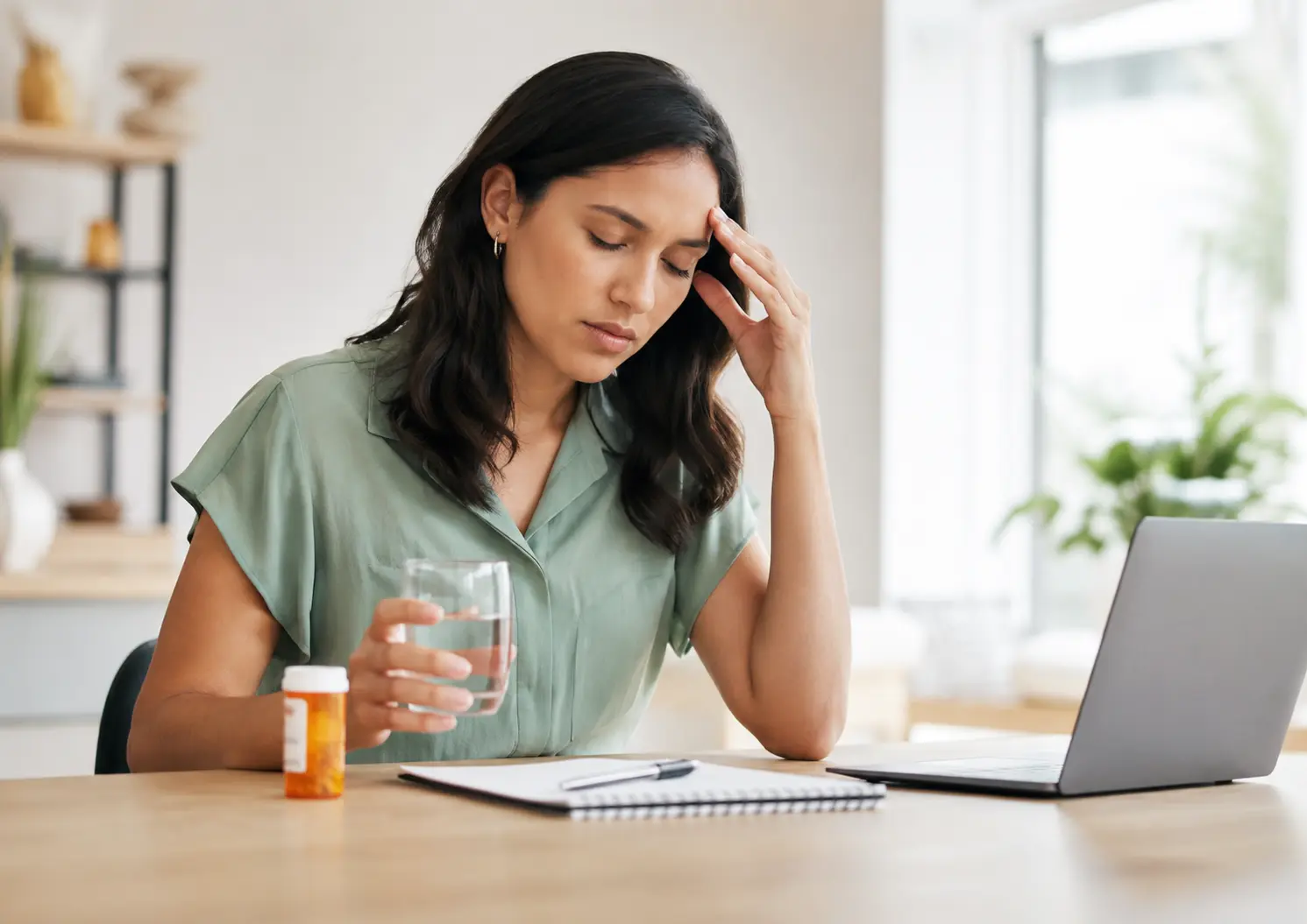 Woman experiencing phentermine side effects while holding water beside medication.